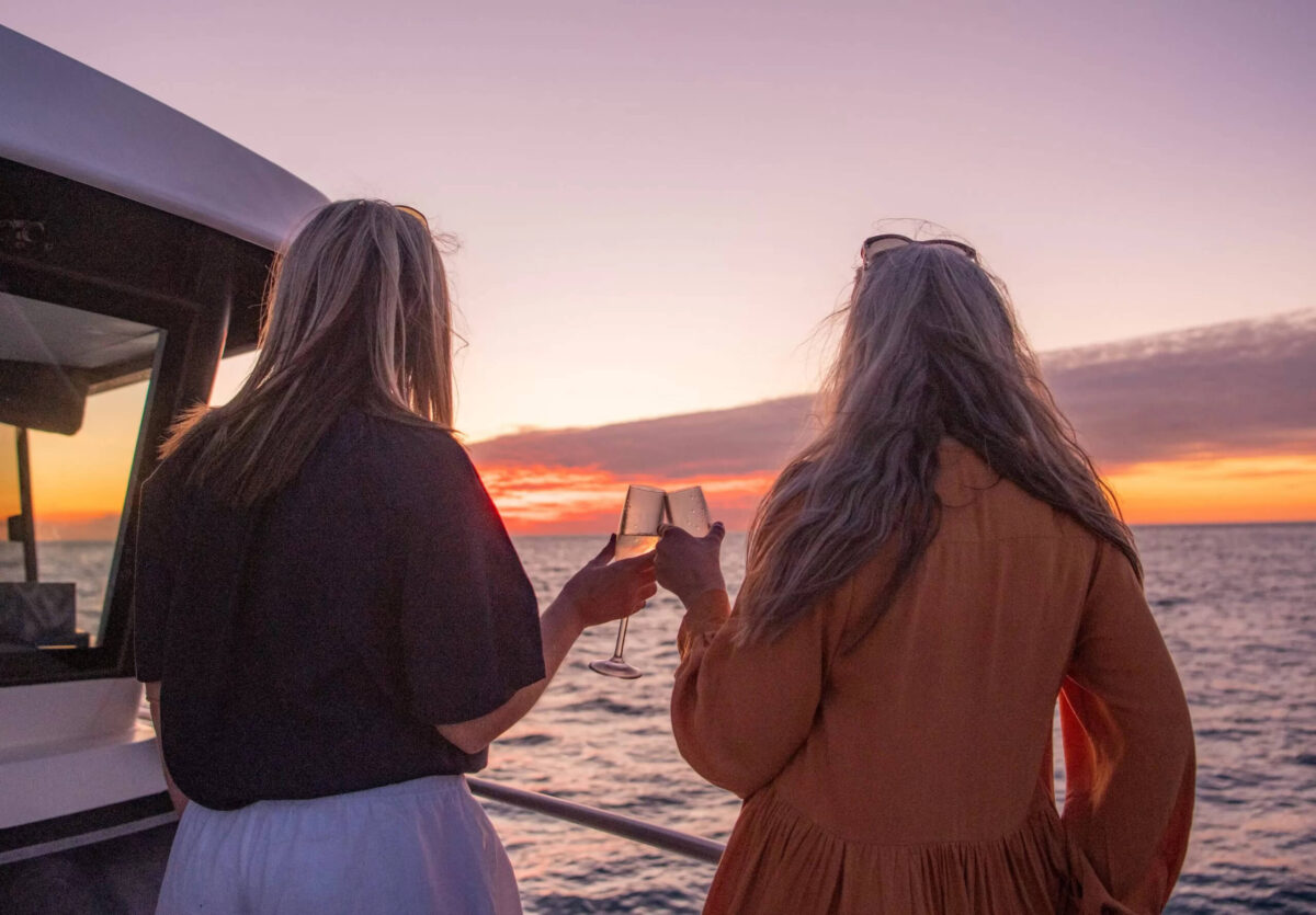 Friends drinking champagne at sunset on Broome fishing charter