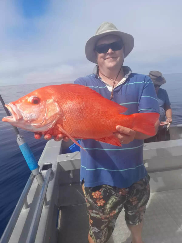 Man holding red emperor fish that he just caught on Broome fishing charter