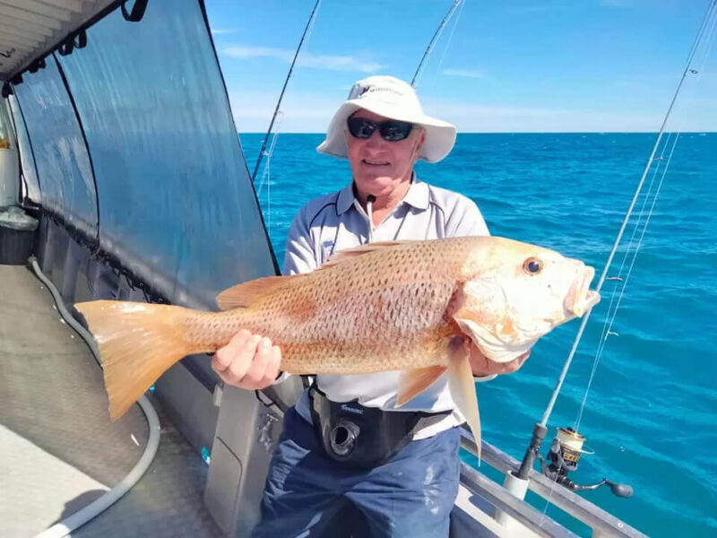 Older man holding a fish just caught on Broome fishing charter